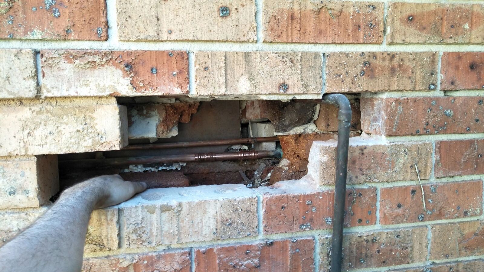 Burst pipe cut out of a brick wall and replaced